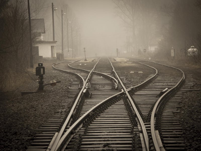 Vías de tren que se bifurcan y se cruzan entre sí en la niebla, en blanco y negro
