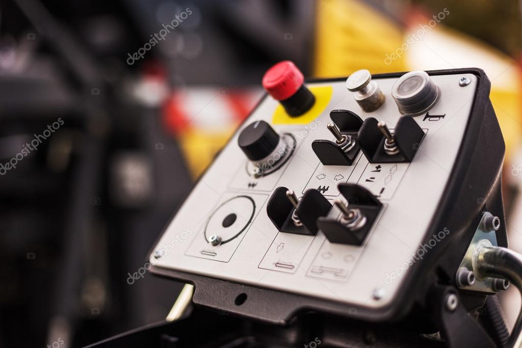 Panel de control portátil de maquinaria industrial con palancas, interruptores y botón de emergencia rojo