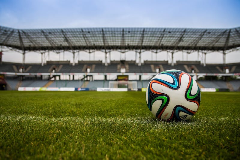 Balón de fútbol sobre el césped de un estadio vacío a vista de suelo