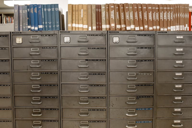 Archivador metálico gris con múltiples cajones etiquetados y bien organizados en una biblioteca o sala de archivos