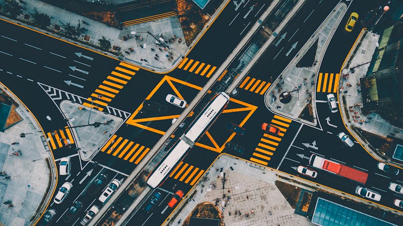 Vista aérea de una gran intersección urbana con cruces de calles, señalización amarilla horizontal pintada en el asfalto y vehículos desde arriba