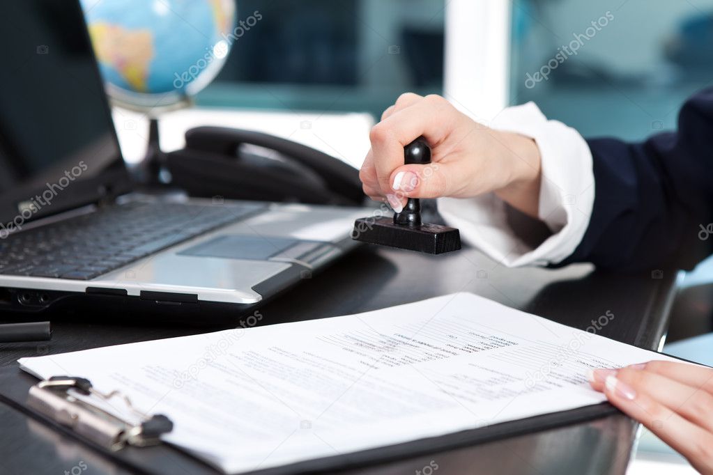 Mano estampando un sello de goma sobre un documento en un escritorio de oficina