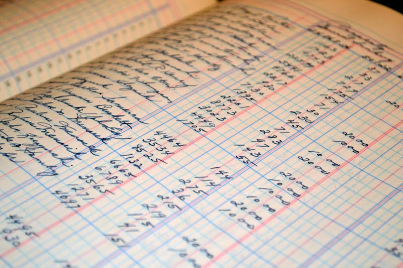Libro de contabilidad abierto con columnas de números manuscritos en cuadrícula sobre papel amarillento